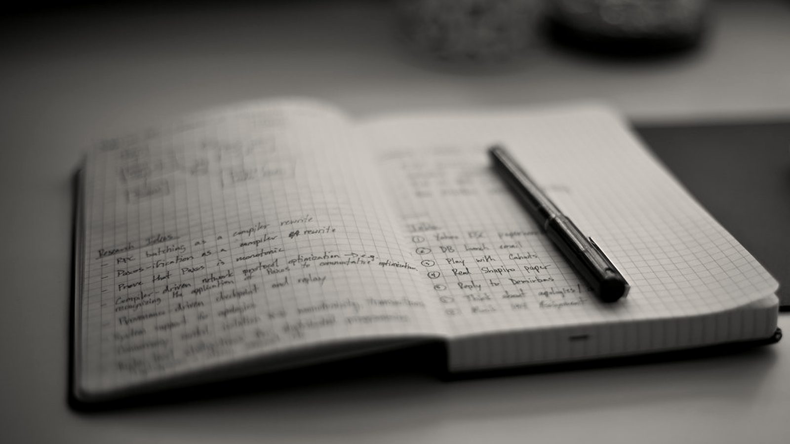 An open working notebook with handwritten notes and a pen